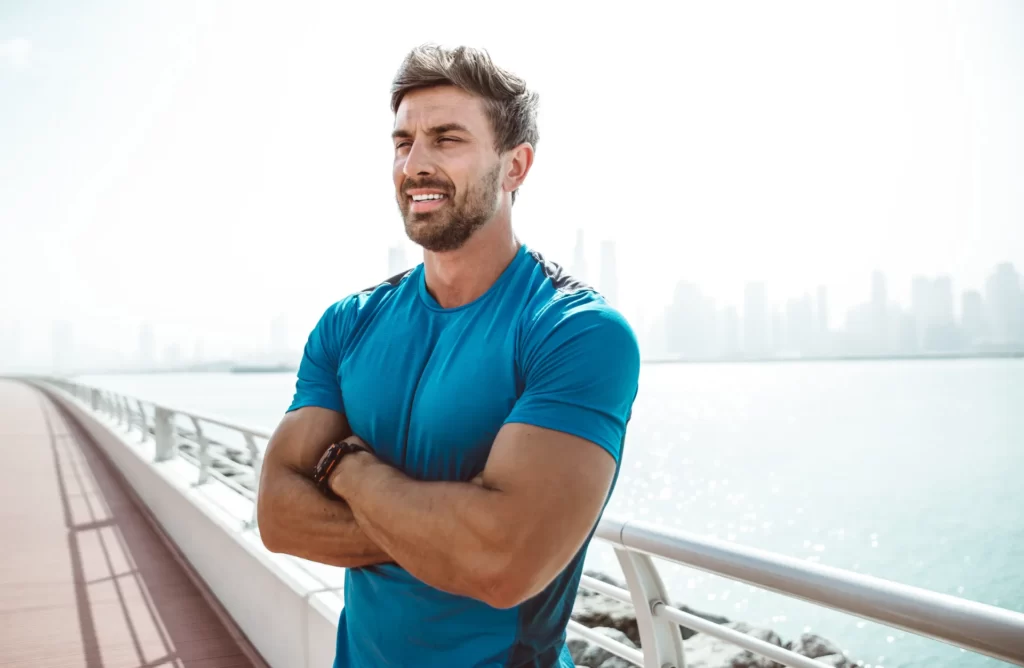 confident man standing near the water on boardwalk utc